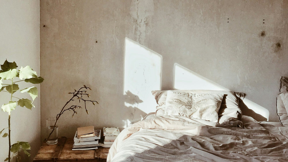 First light crossing a linen bed and a stack of books on a bedside table, the quiet recovery window magnesium glycinate is taken for